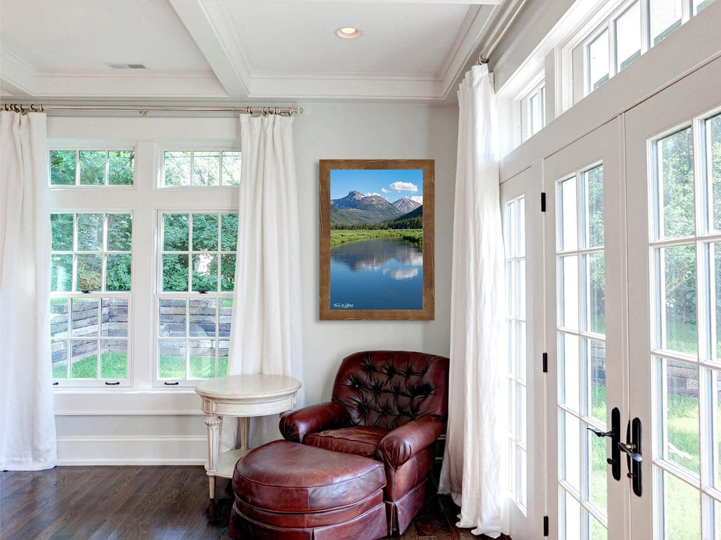 framed photograph of mountains reflecting in river on home wall.