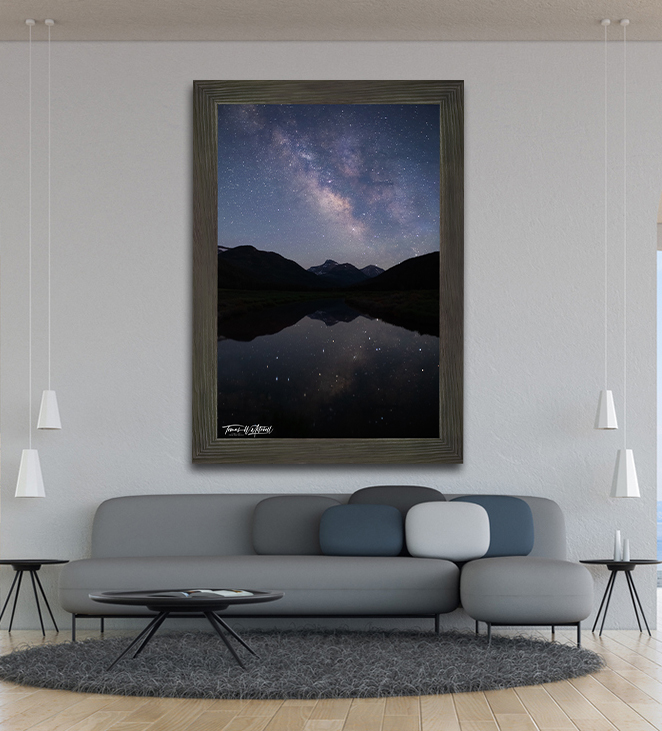 framed photograph of Milky Way night sky over mountains on home wall.